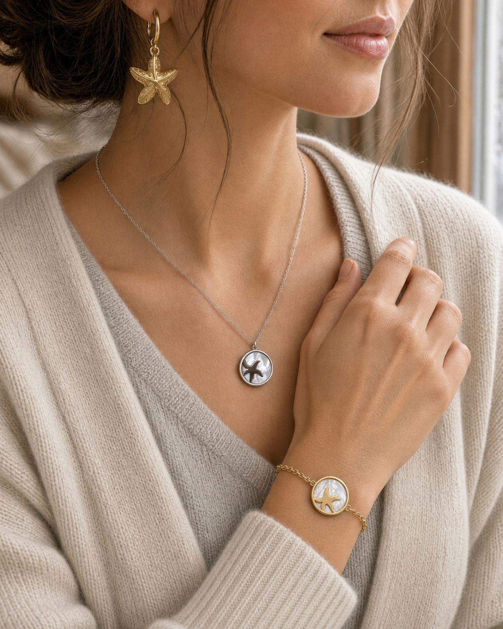 woman with dark hair wearing silver starfish in sea shell necklace, golden starfish in sea shell bracelet and gold starfish earrings